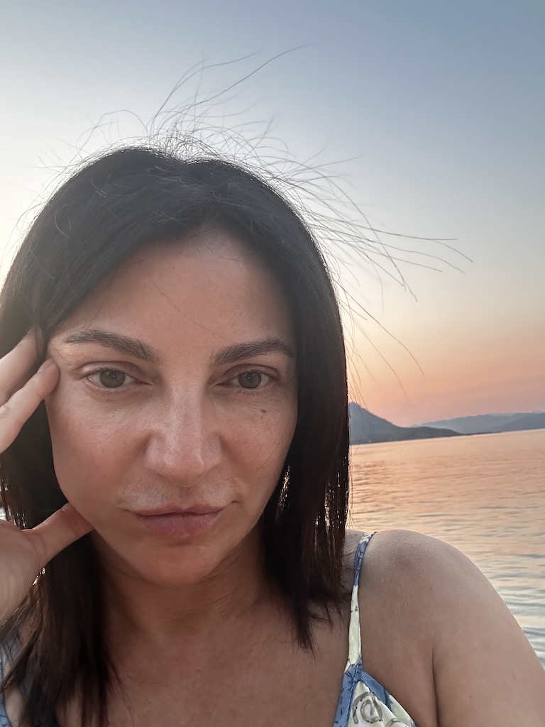 Eteri McKenzie looking thoughtful at sunset by the sea, symbolising emotional reflection and inner calm.