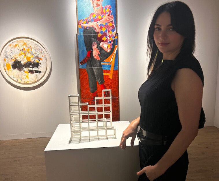 Eteri McKenzie standing in an art gallery surrounded by vibrant paintings, representing the connection between creativity, neuroscience, and emotional healing.