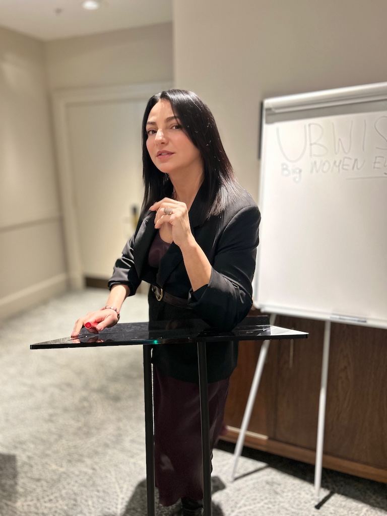Eteri McKenzie standing at a podium and speaking during a neuroscience based hypnotherapy session in Edinburgh.